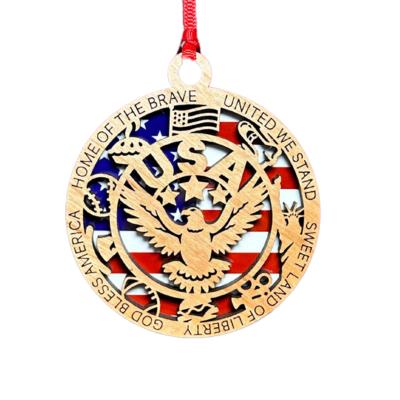 Patriotic wooden eagle ornament with a laser-cut design layered over an American flag background. Features an eagle centerpiece, “USA” text, and engraved border phrases including “Home of the Brave,” “United We Stand,” and “God Bless America.” Finished with a red hanging ribbon.