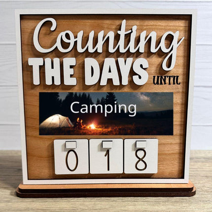 Wooden interchangeable countdown sign displaying “Counting The Days Until” with Camping plate featuring a tent and campfire at night, and number tiles showing 018 on a tabletop stand.