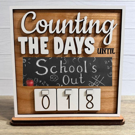Wooden interchangeable countdown sign displaying “Counting The Days Until” with School’s Out chalkboard-style plate and number tiles showing 018 on a tabletop stand.