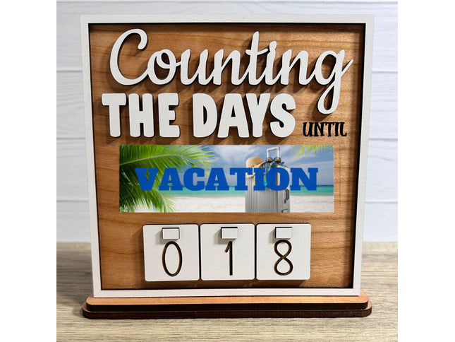 Wooden interchangeable countdown sign displaying “Counting The Days Until” with Vacation plate featuring a beach scene and suitcase, and number tiles showing 018 on a tabletop stand.