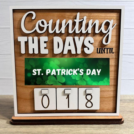 St. Patrick's Day countdown calendar. The sign reads "Counting the Days Until St. Patrick's Day." The calendar shows "018" days remaining. The background is a light brown wood with a white frame.