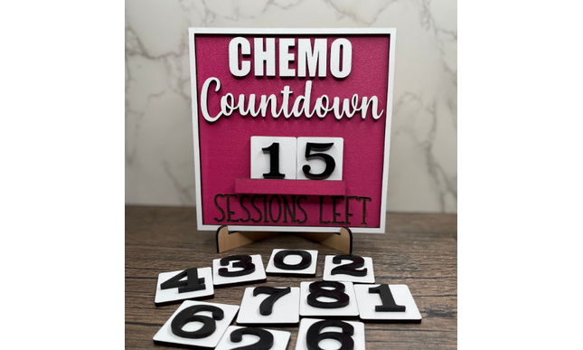 Pink chemo countdown sign with interchangeable number tiles laid out for tracking treatment sessions